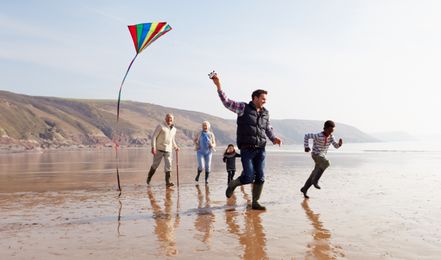 Photo of multigenerational family flying a kite on the beach